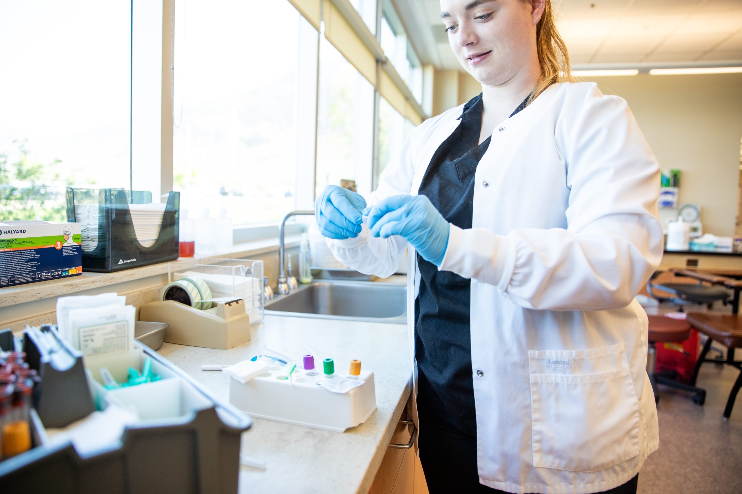 Phlebotomy student preparing a test tube for a blood draw.