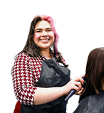Cosmetology student smiling and cutting a customers hair