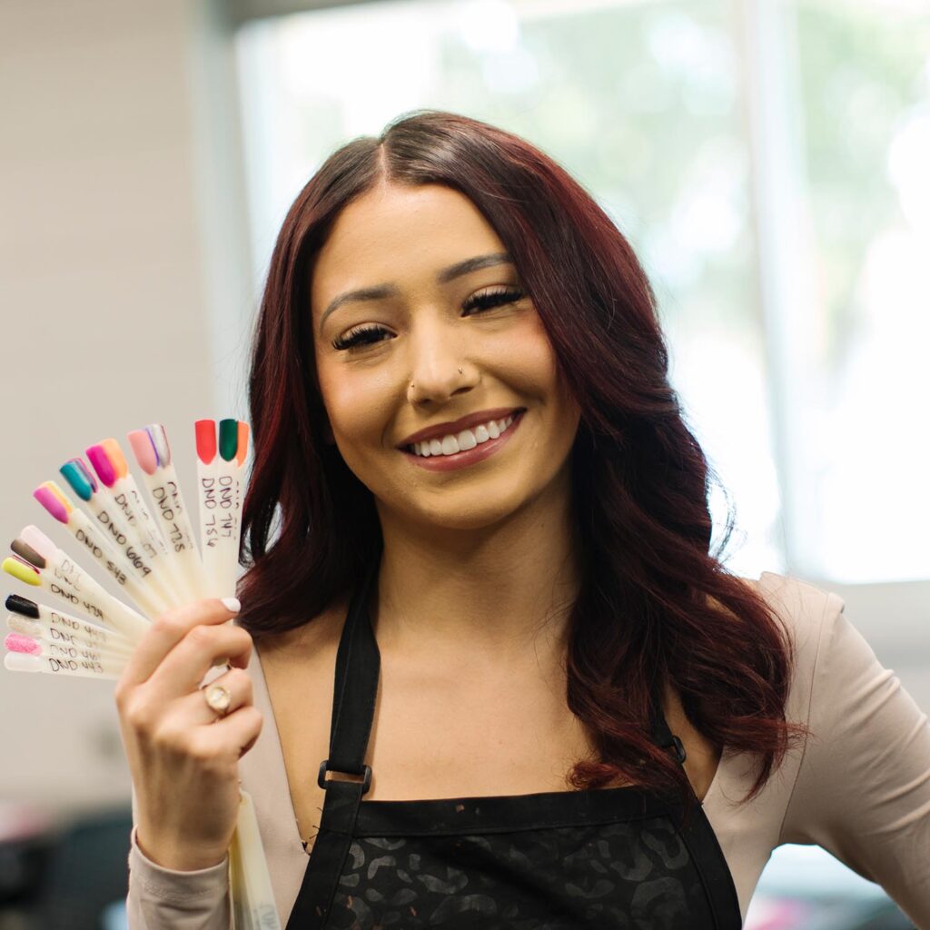 Woman with dark hair holding colorful paint cards and smiling at camera.
