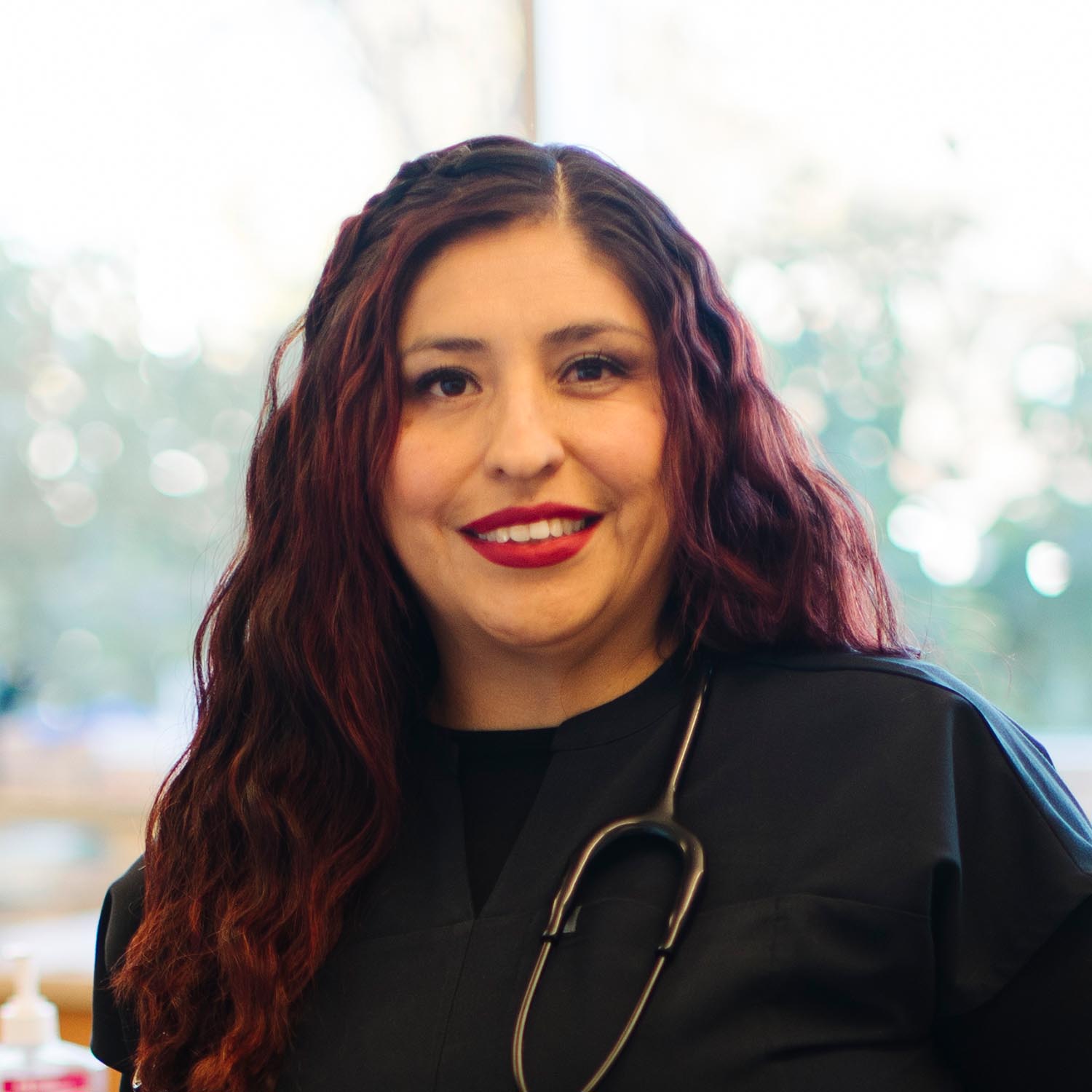 Smiling woman in black scrubs with red hair in a professional setting.