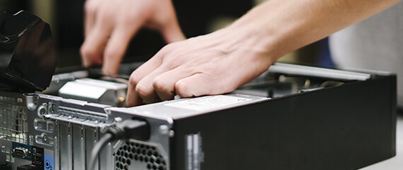 Hands opening and working inside a desktop computer tower, representing the computer repair services available through OTECH's campus services program