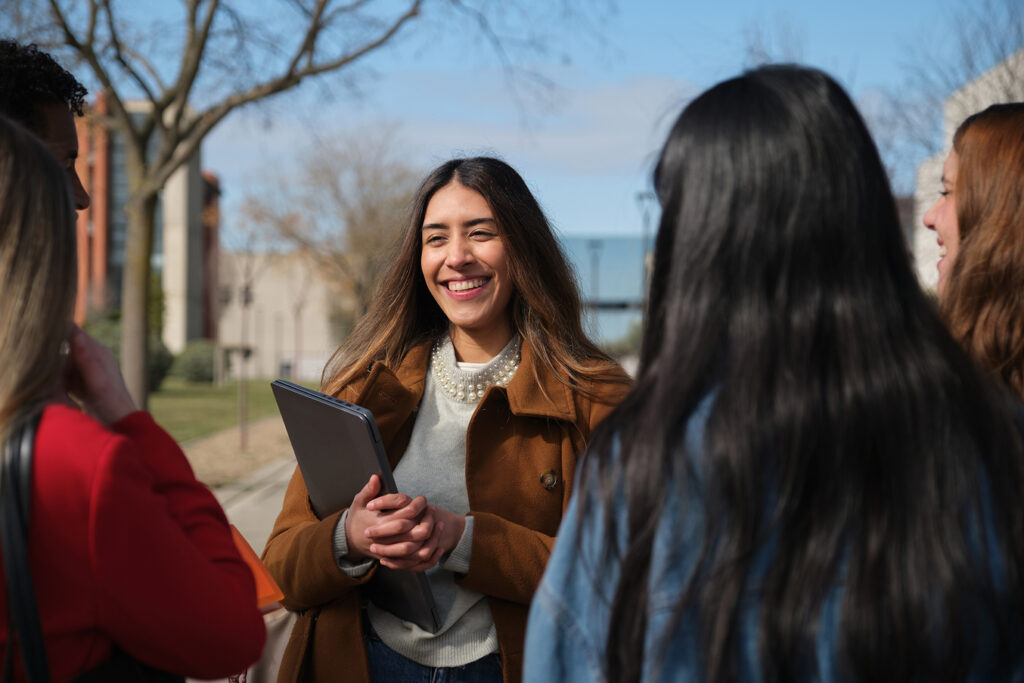 Students gathering outside of school standing, smiling together